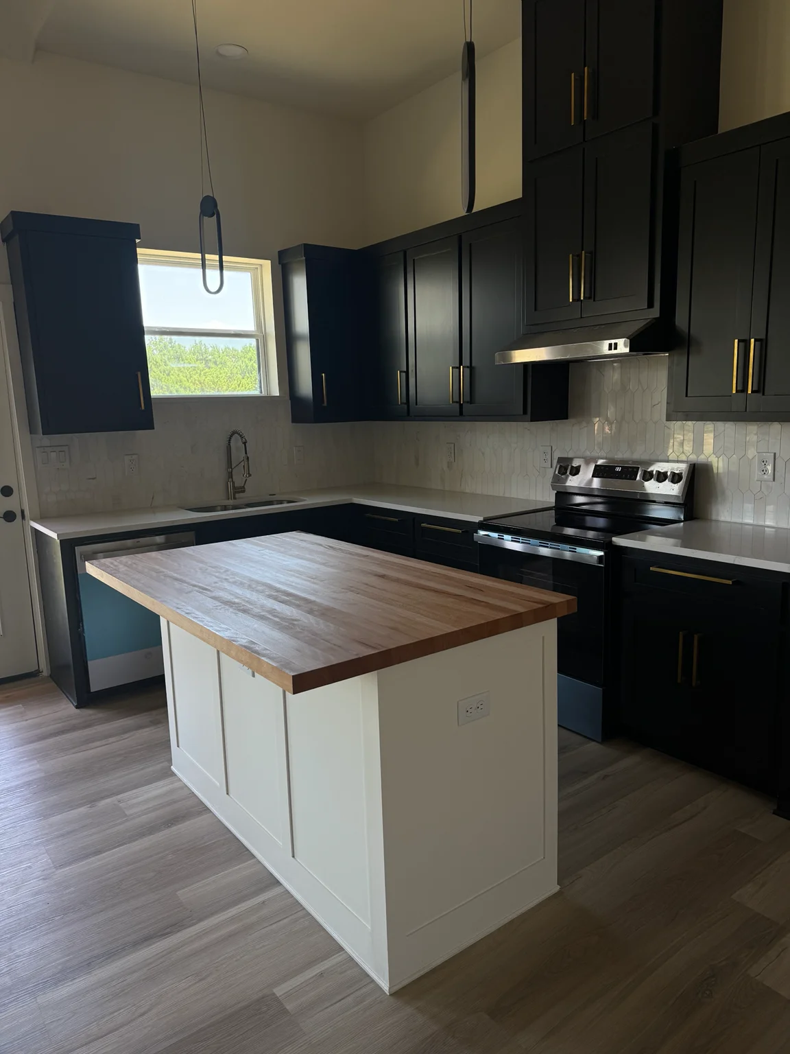 Same kitchen finished with dark cabinets and a wood island top